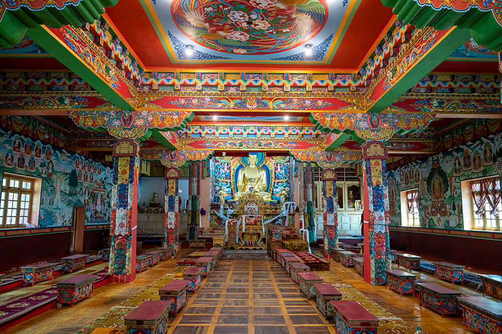 The main prayer hall at Phyang Monastery, with rows of low seating and painted walls